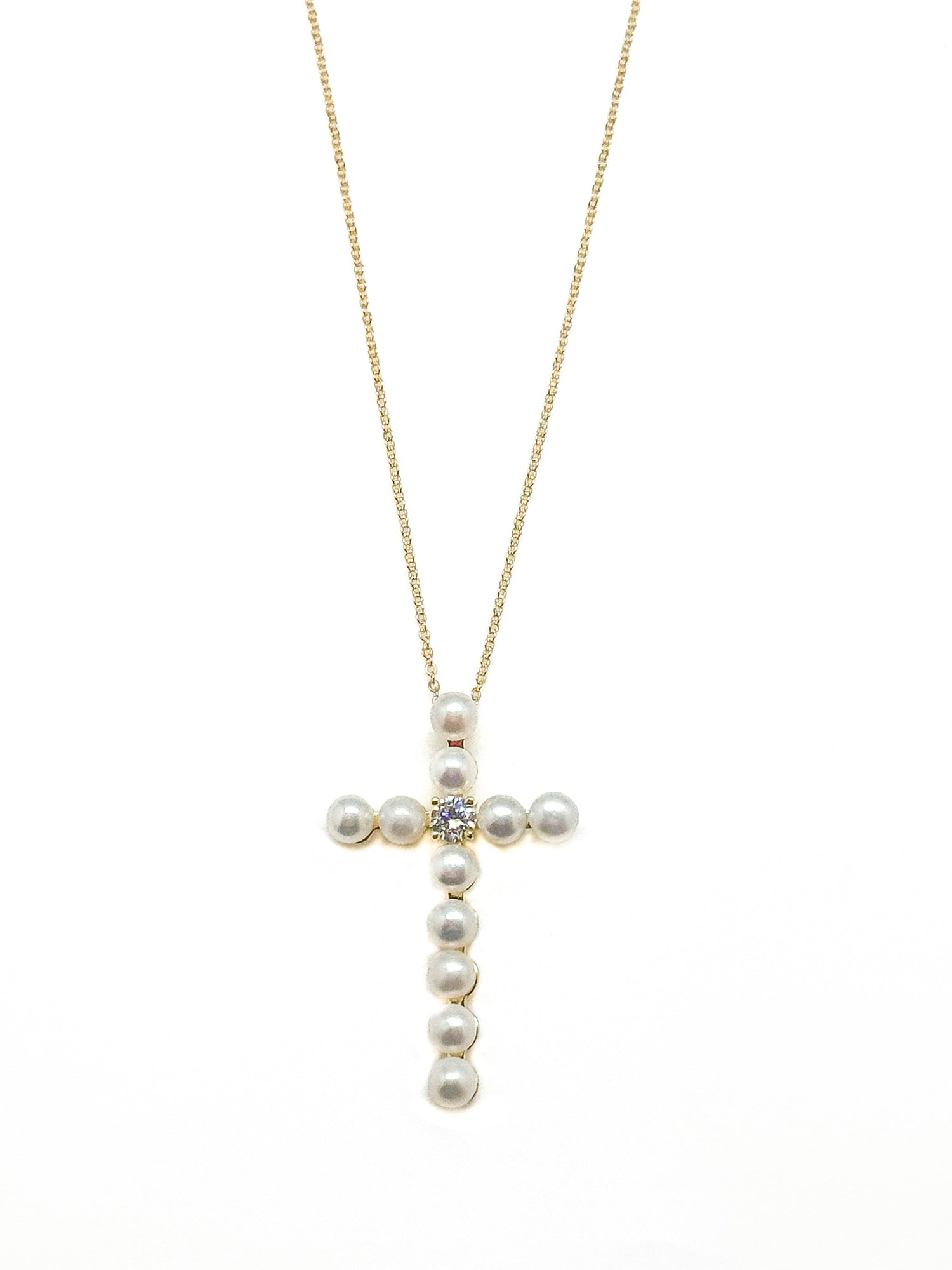 Pearl cross necklace on a gold chain against a white background