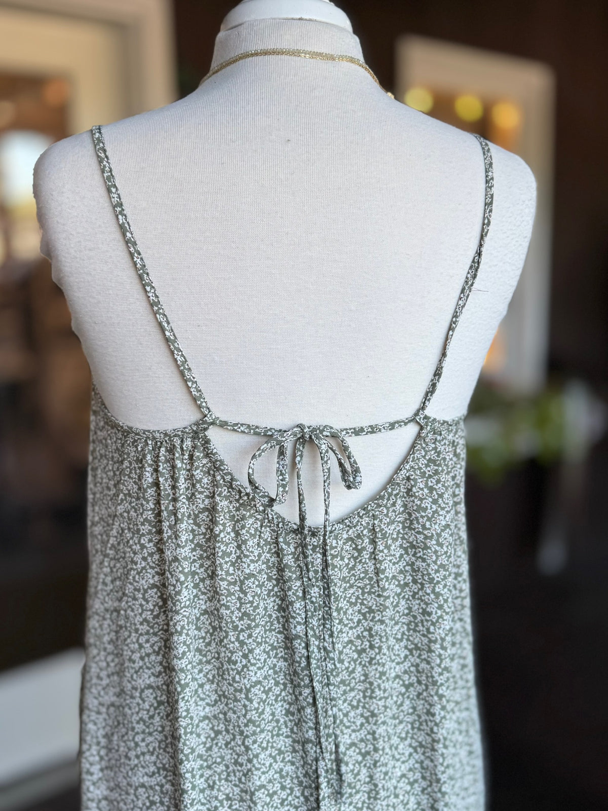 Close-up of olive green floral maxi dress showing the open back, spaghetti straps and adjustable tie at Ardor Boutique.