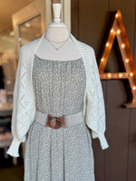Close-up of ivory open-knit cardigan with textured diamond pattern and ribbed trim layered over a floral dress at Ardor Boutique.