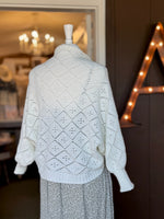 Back view of ivory open-knit cardigan showing the textured diamond knit pattern, relaxed sleeves and ribbed hem at Ardor Boutique.