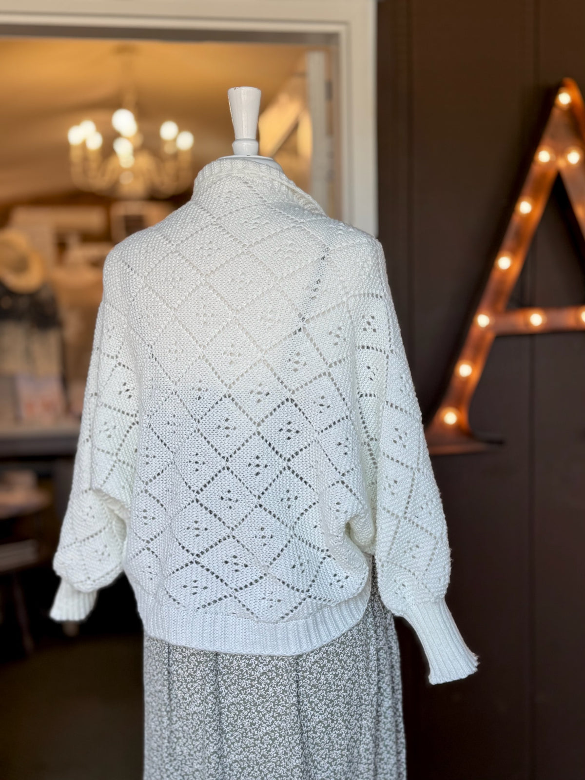 Back view of ivory open-knit cardigan showing the textured diamond knit pattern, relaxed sleeves and ribbed hem at Ardor Boutique.
