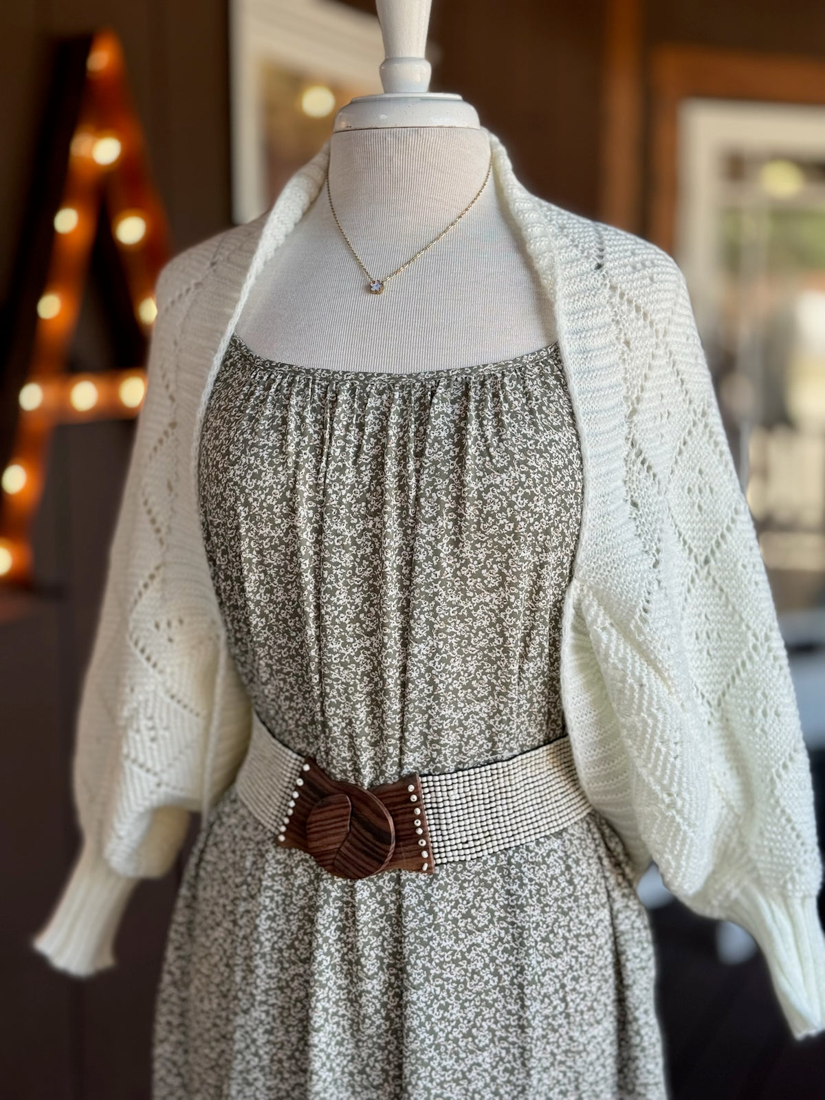 Ivory open-knit cardigan with diamond knit pattern and ribbed cuffs layered over a floral maxi dress at Ardor Boutique.