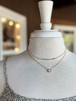 Delicate gold clover pendant necklace layered with a gold-tone beaded necklace on a mannequin at Ardor Boutique.