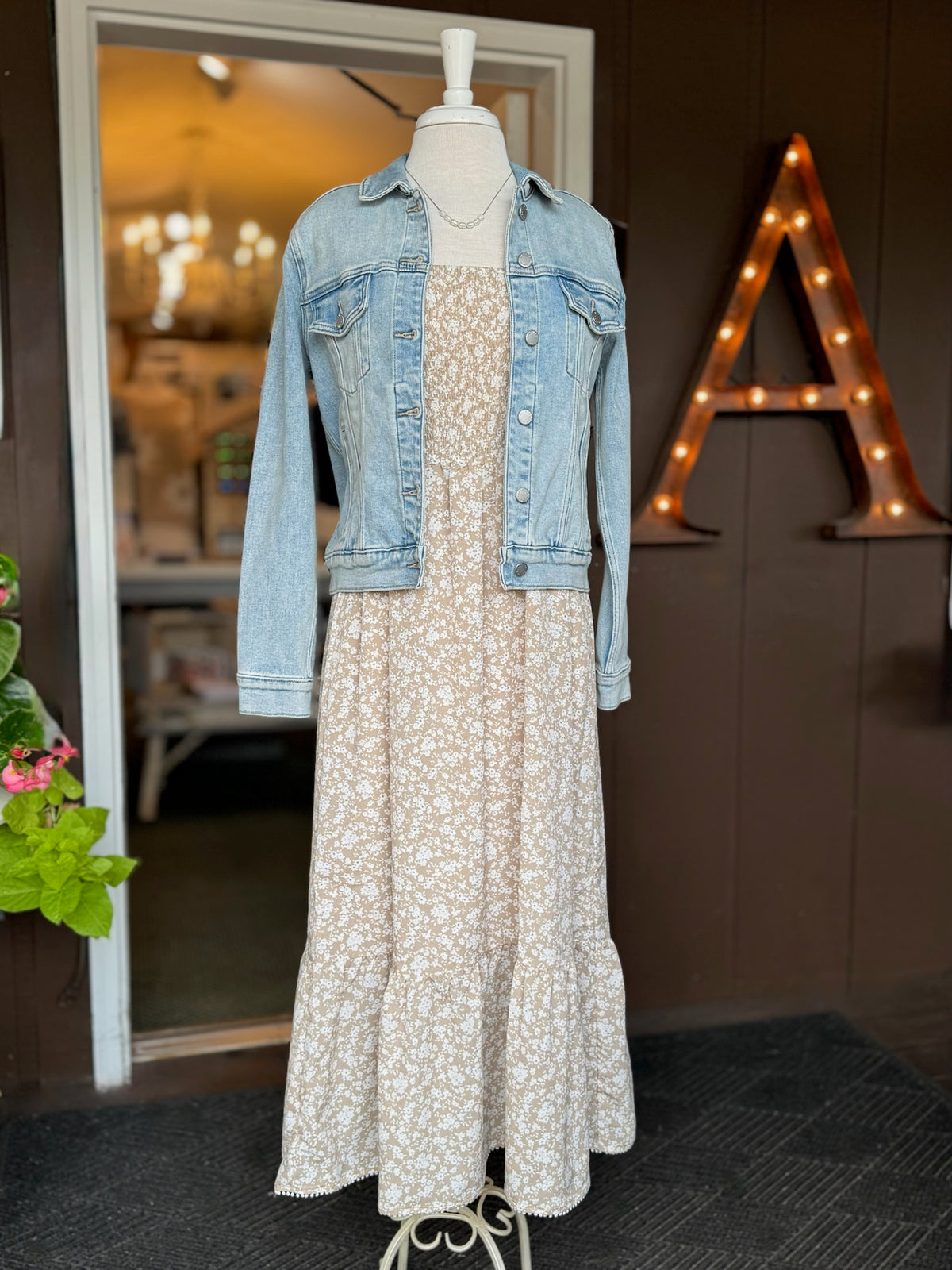 Beige floral maxi dress with a smocked bodice, square neckline and ruffle straps layered with a light wash denim jacket at Ardor Boutique.
