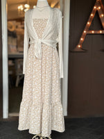 Beige floral maxi dress layered with a lightweight ivory tie-front cardigan at Ardor Boutique.