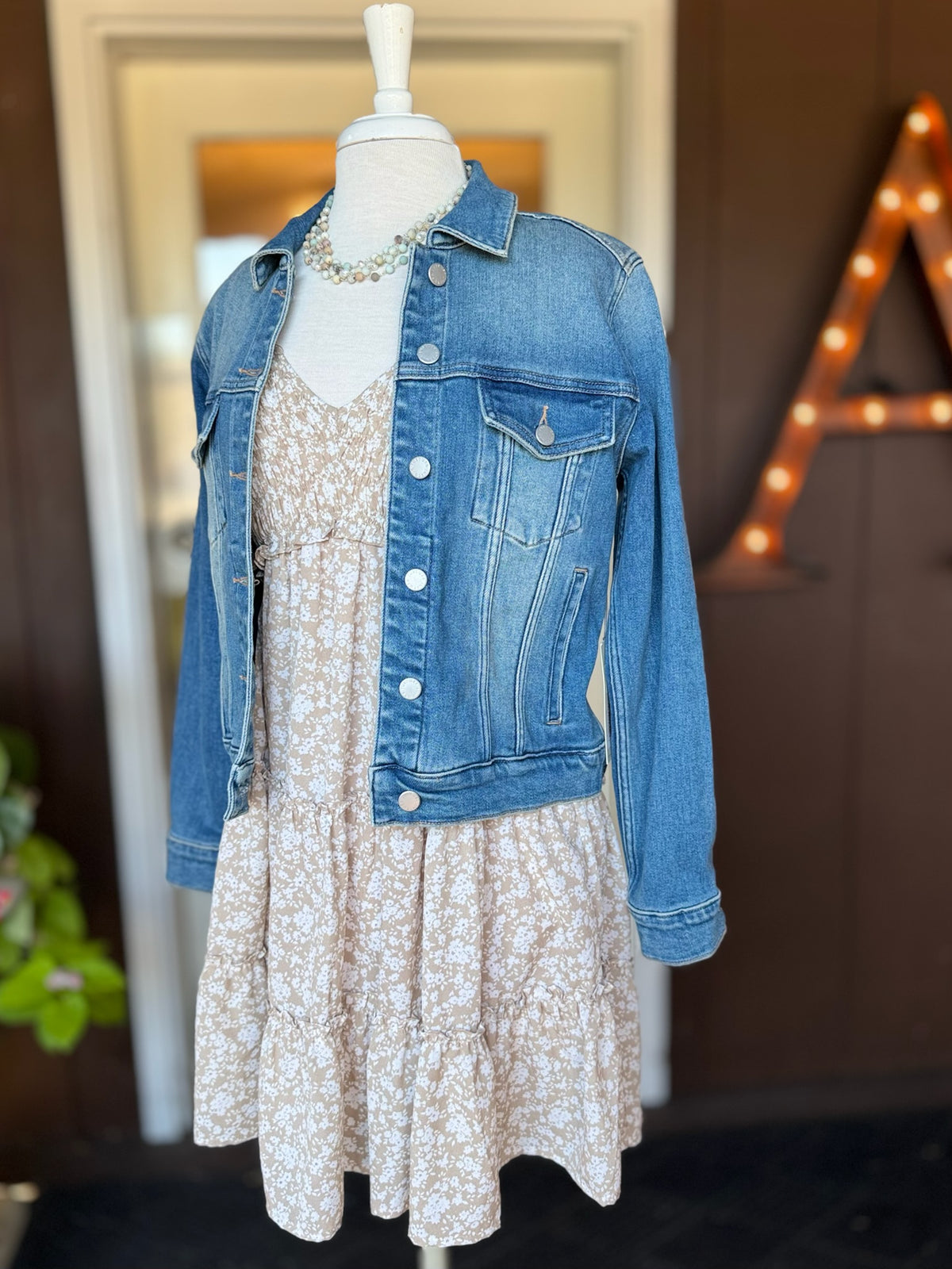 Beige and white floral dress layered with a medium wash denim jacket for an easy transitional outfit at Ardor Boutique.
