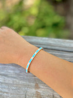 Turquoise and gold crystal cuff bracelet worn on wrist.