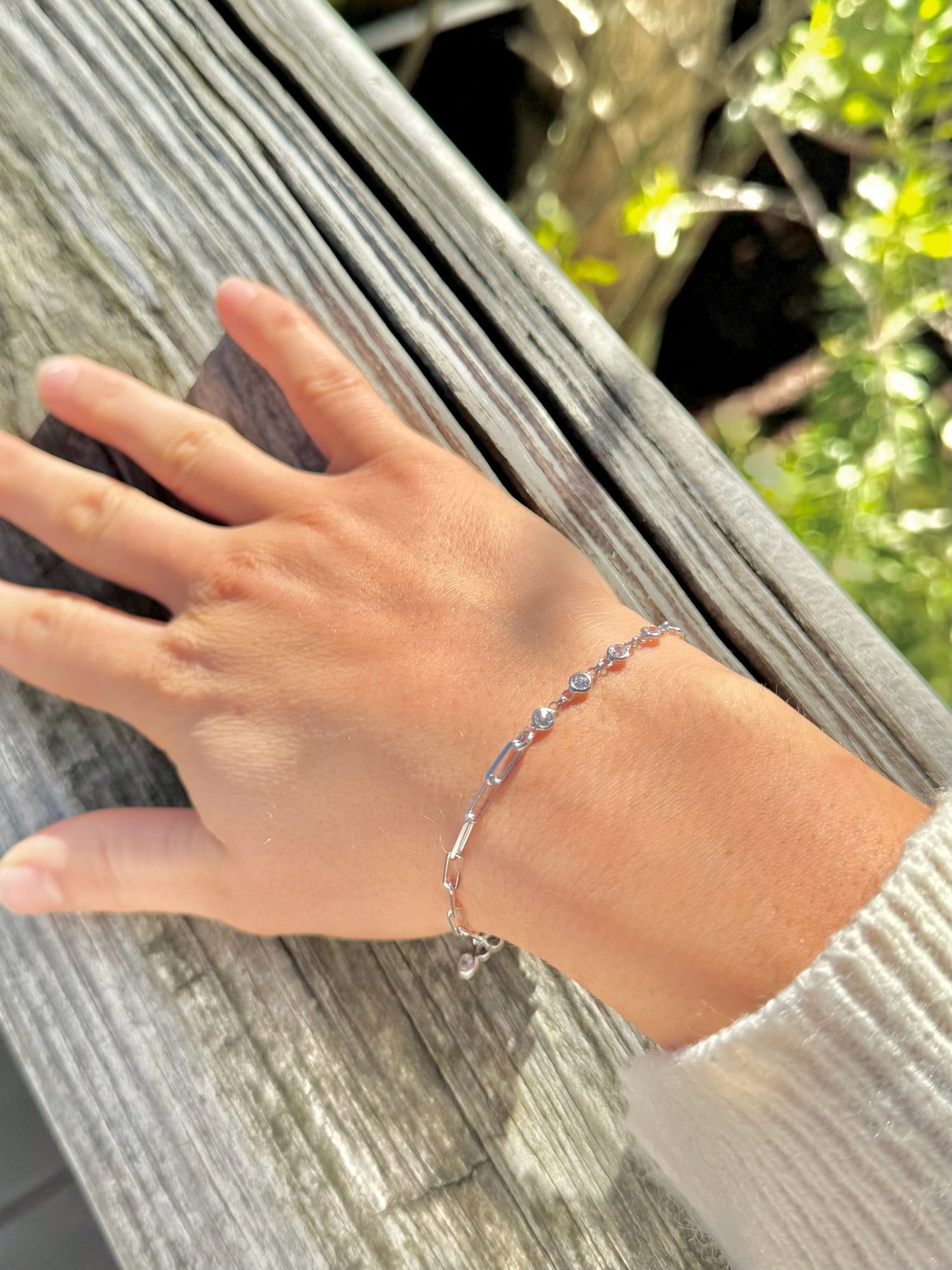 Hand wearing a bracelet with a blurred natural background