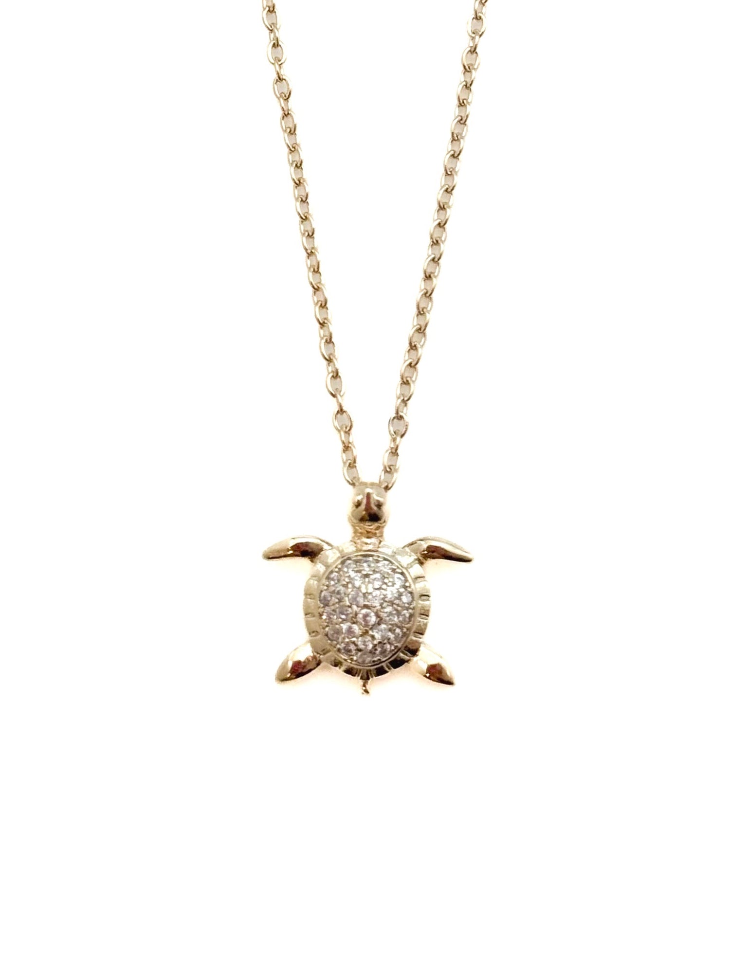 Turtle pendant necklace with pavé stone detailing on a fine chain against a white background