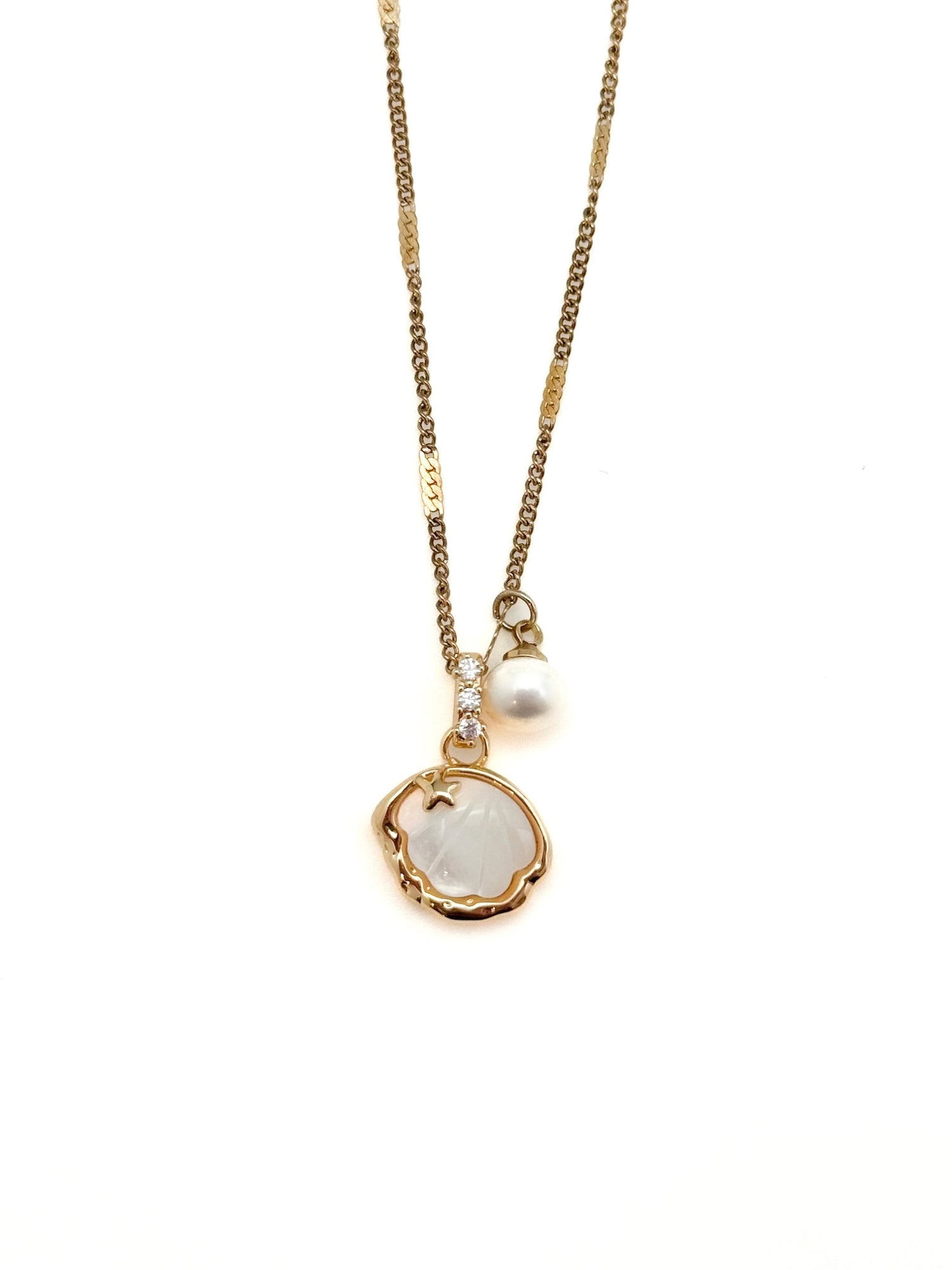 Pendant necklace with sculpted charm, pavé accent, and small drop detail on a fine chain against a white background