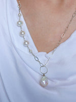 Model wearing the Grace pearl nh necklace in sterling silver, featuring asymmetrical pearls and a large dancing drop pearl on an open link chain.