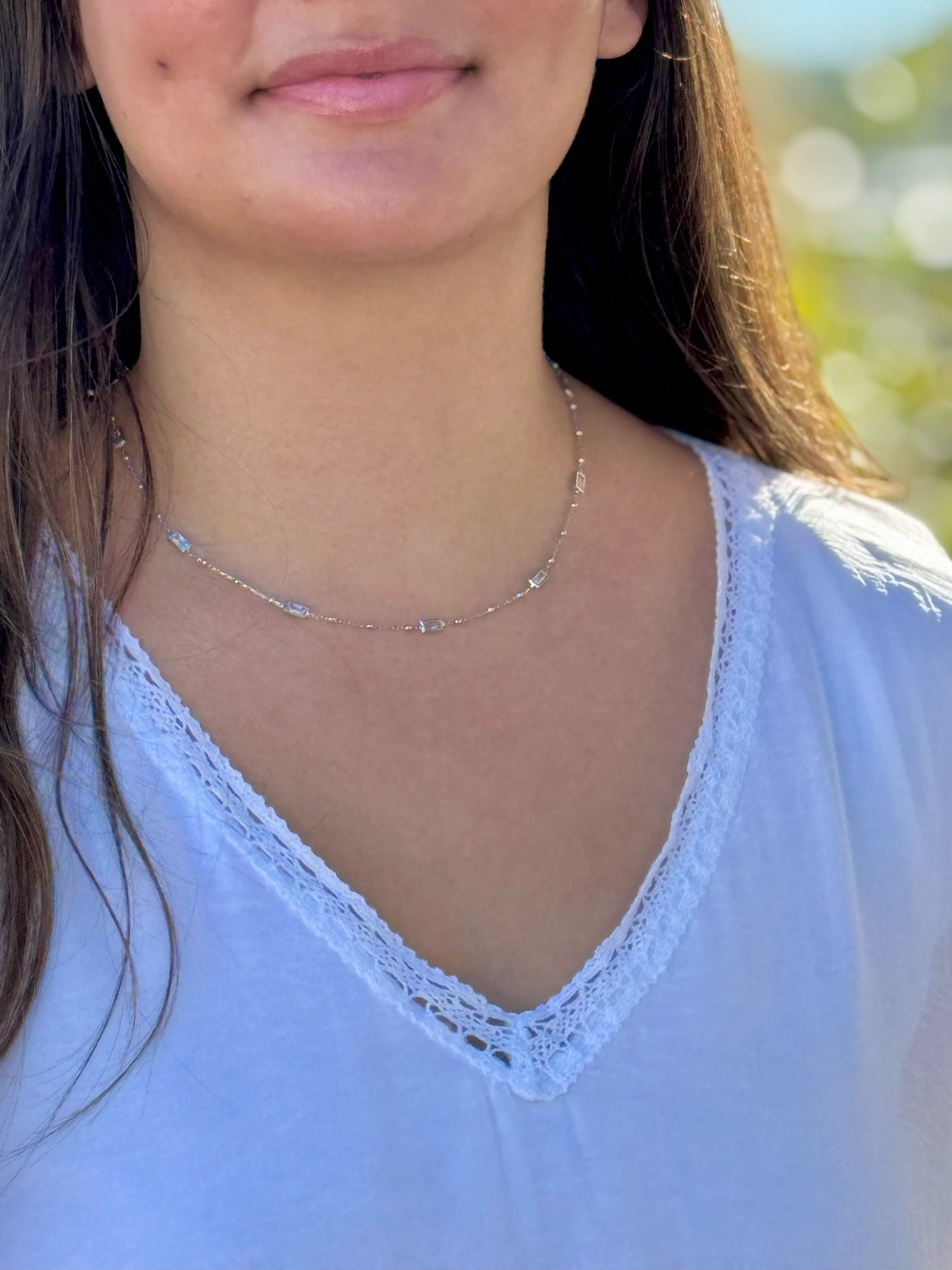 Woman wearing a delicate necklace with a blurred natural background
