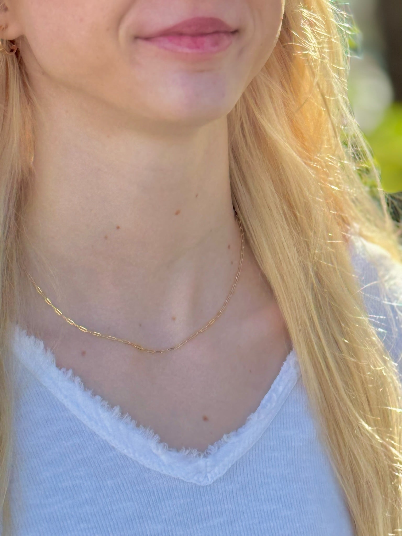 Close-up of a person wearing a gold necklace with a blurred background