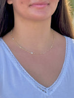 Person wearing a delicate gold necklace with a blurred background