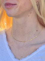 Close-up of a person wearing a gold necklace with a blurred background