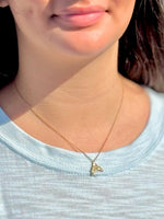 close-up of sparkly gold over sterling silver dolphin tail pendant necklace worn at the collarbone.