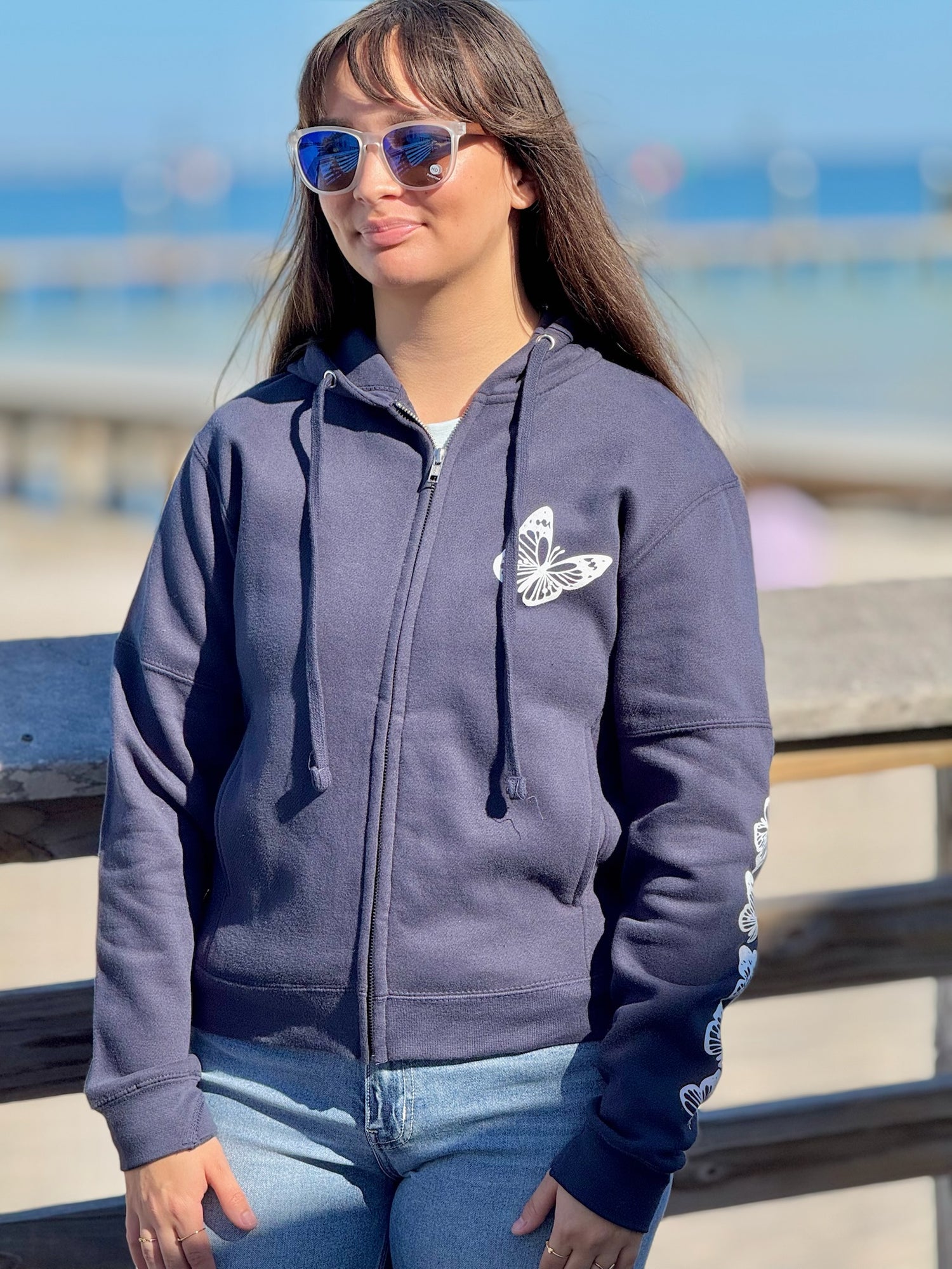 Women’s butterfly Zip-up hoodie with chest butterfly graphic, butterfly sleeve design, drawstring hood and ribbed trim at Ardor Boutique.