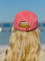 Person wearing a Coral cap with a blurred beach background