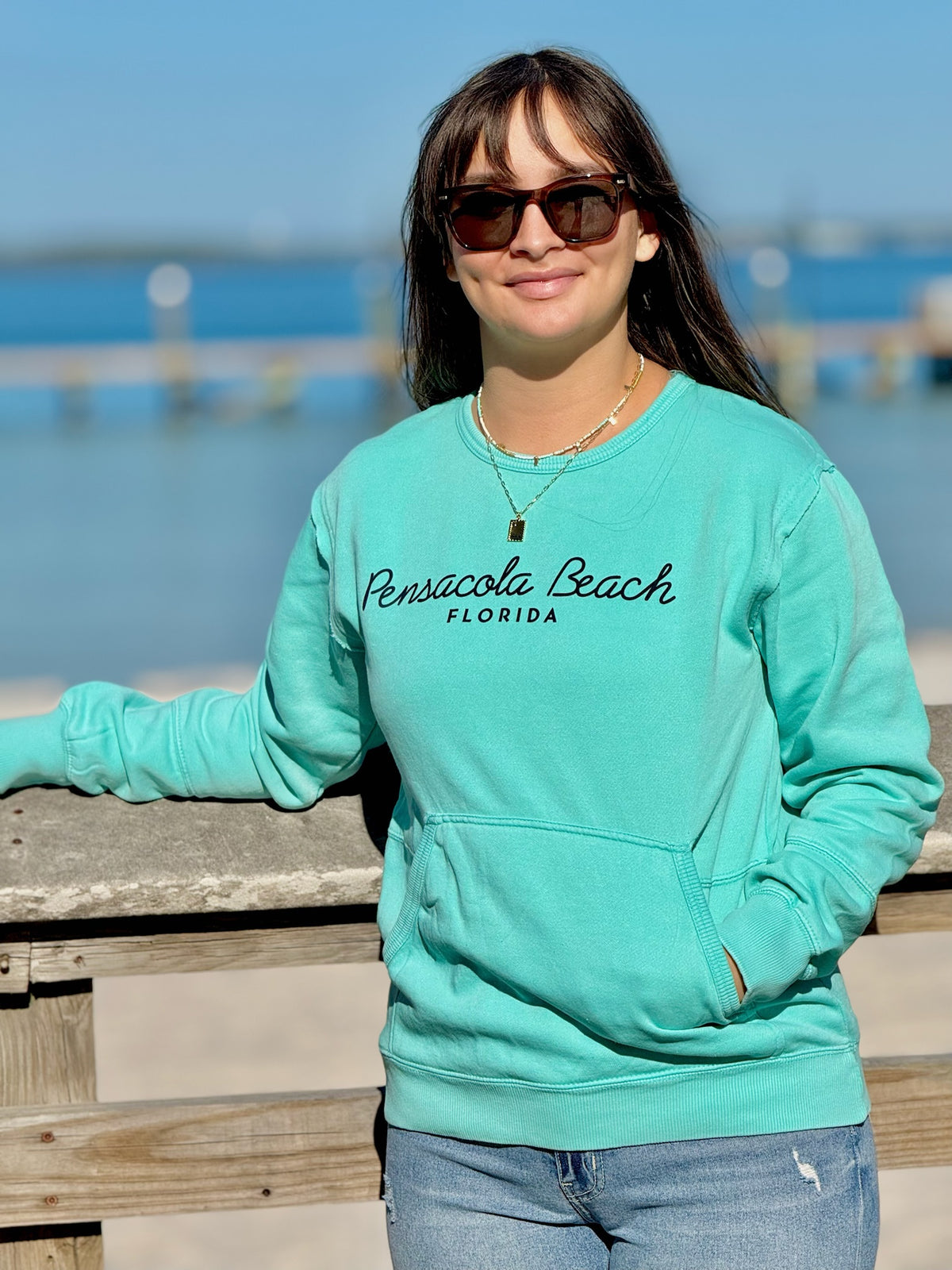 Pensacola Beach Icons Pocket Sweatshirt in aqua with front kangaroo pocket and Pensacola Beach Florida script graphic at Ardor Boutique.