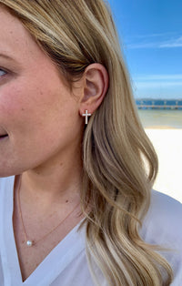 Gold with small pearl detail stud cross earrings in ear