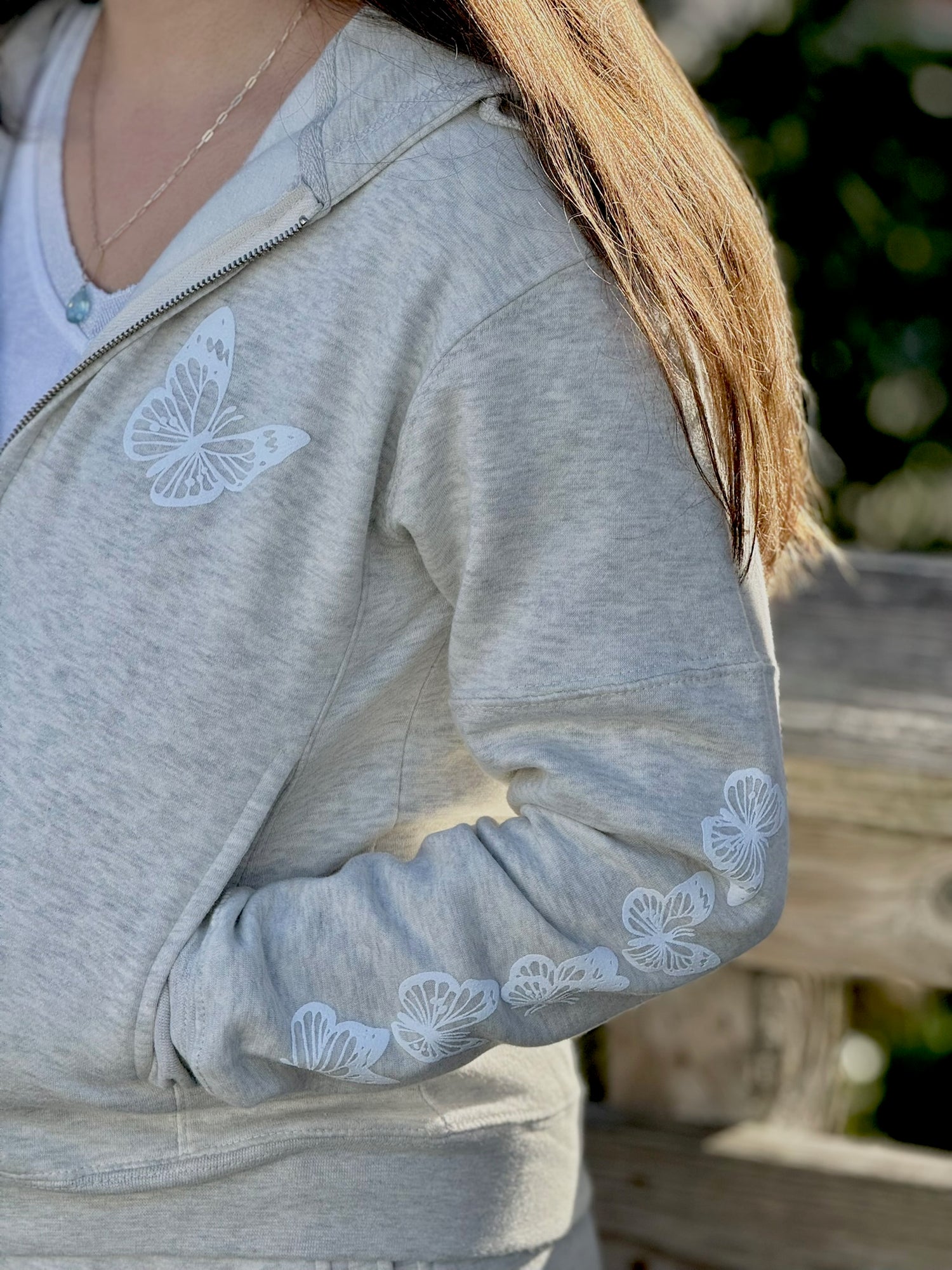 Women’s butterfly Zip-up hoodie with chest butterfly graphic, butterfly sleeve design, drawstring hood and ribbed trim at Ardor Boutique.