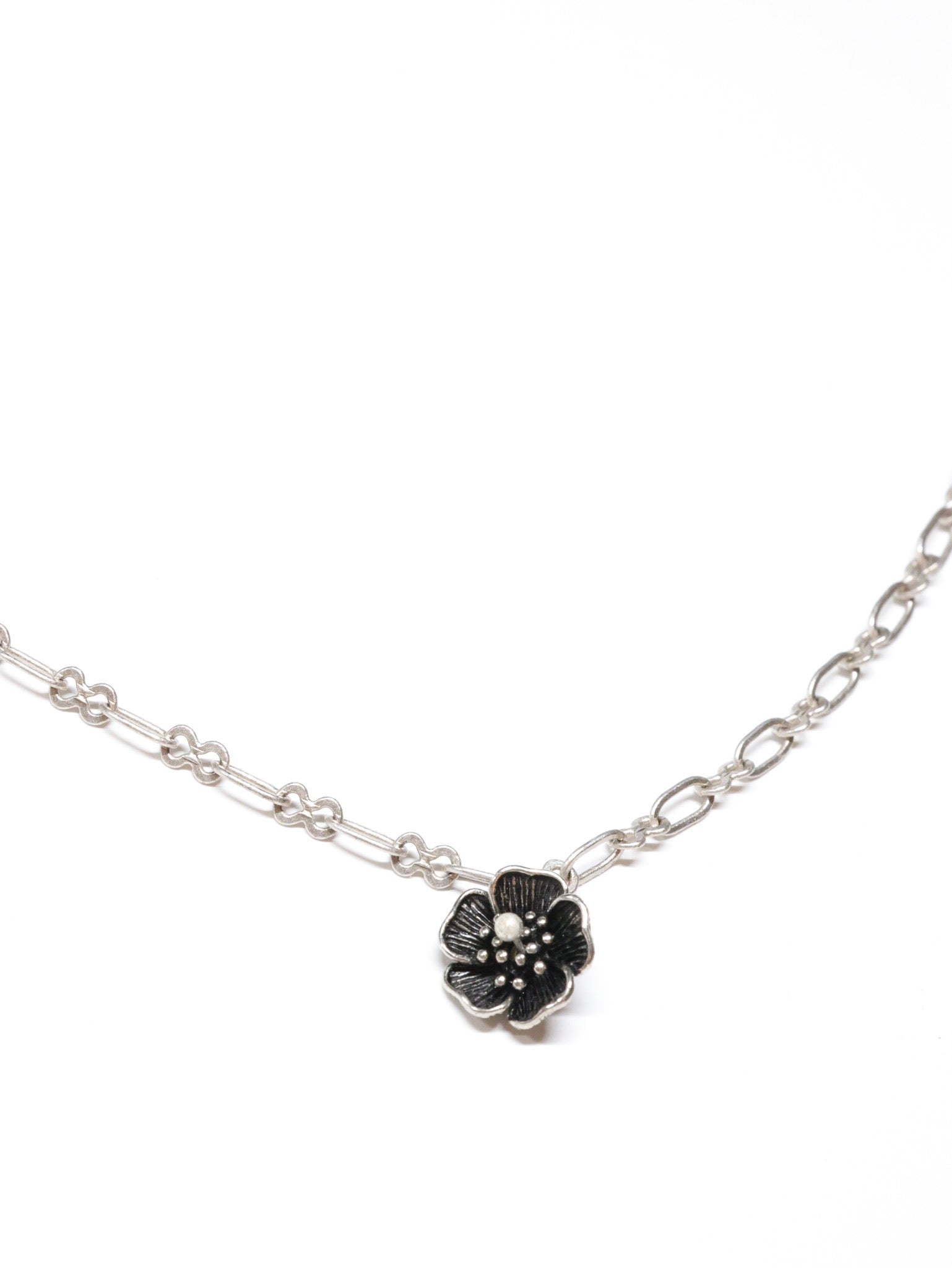 Close-up of a silver necklace with a five-petal flower pendant and dual-link chain – Five Fold Bloom Necklace in antiqued silver