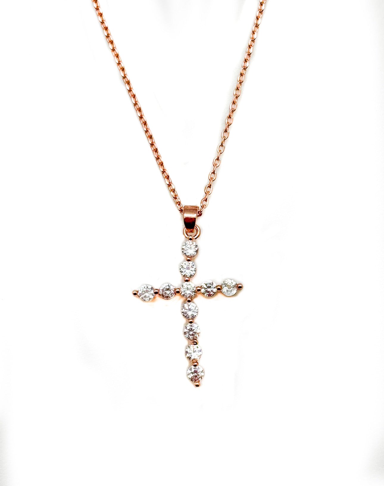 Rose gold cross pendant necklace on a white background