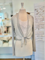 Light gray cardigan with lace detailing on a mannequin in a blurred indoor setting