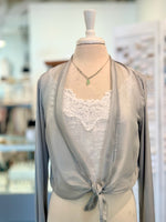 Light gray cardigan with lace detailing on a mannequin in a blurred indoor setting