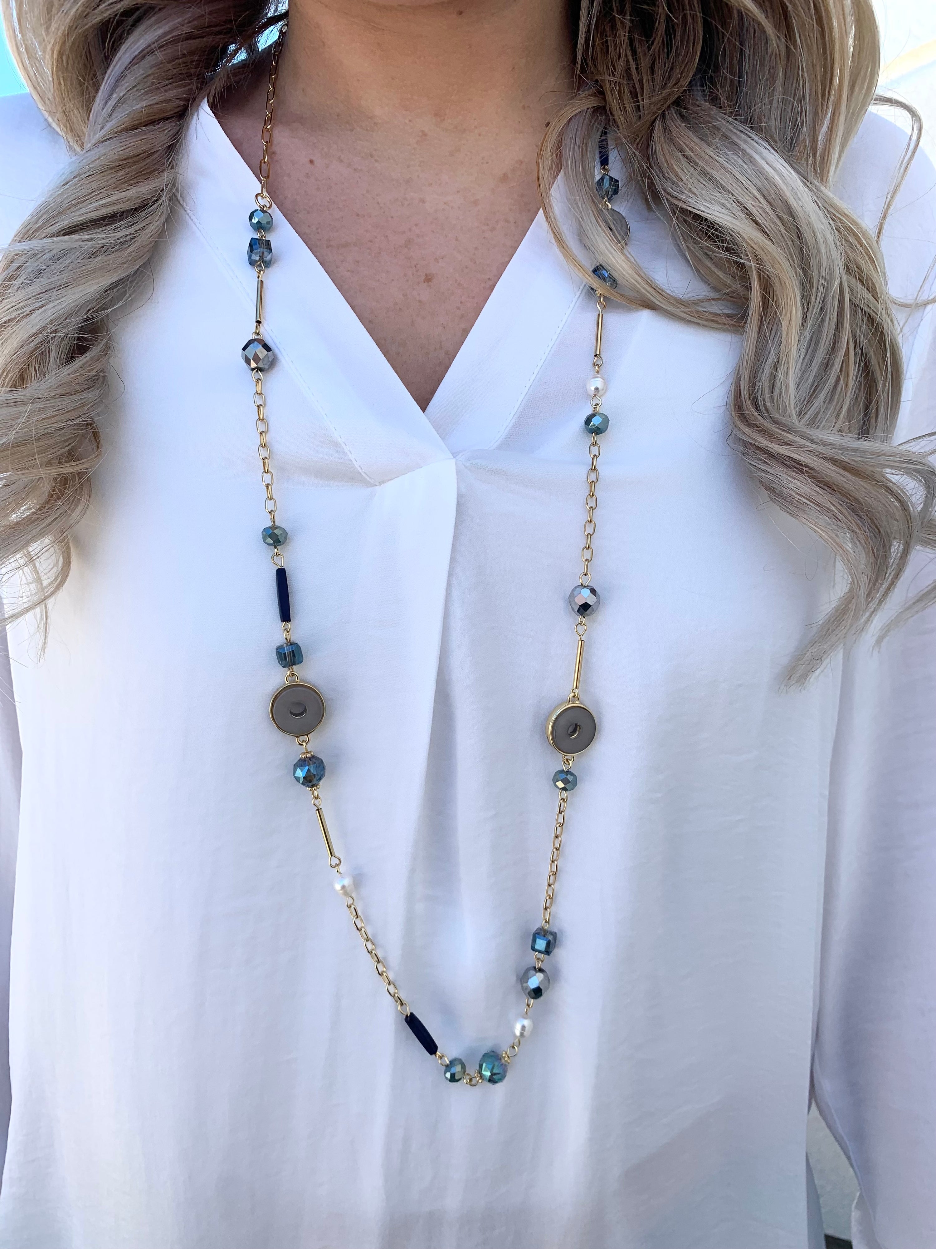 Faryn Necklace. Gold chained with blue and pearl bead accents on model.