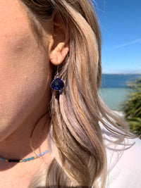 Silver and blue dangle earrings on ear