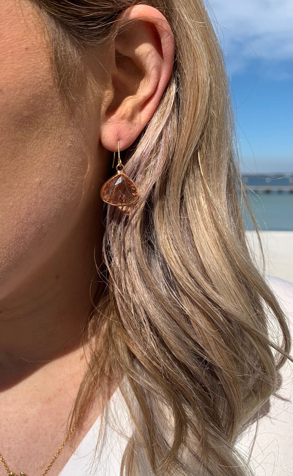 Kassie Gold Dangle earrings with a orange toned crystal in ear
