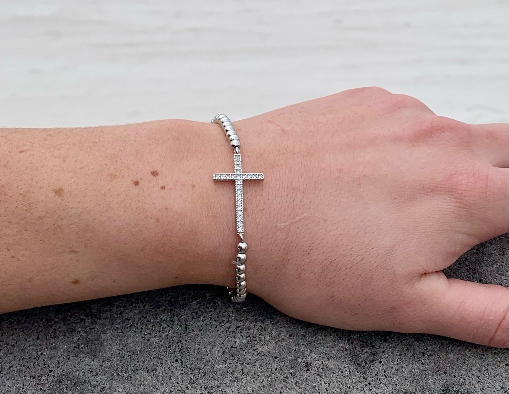 Silver beaded cross bracelet on model. 
