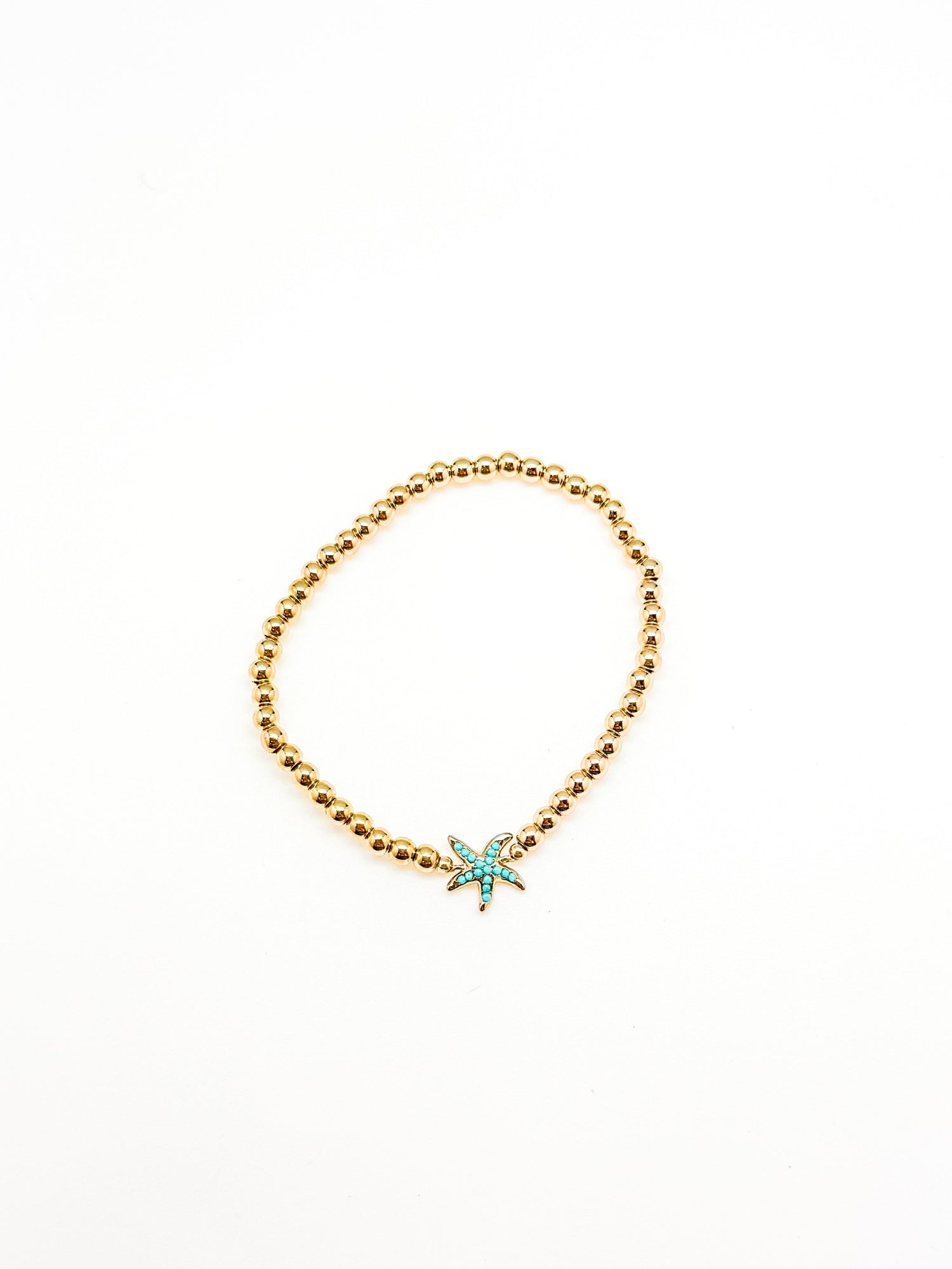 Gold beaded bracelet with a star-shaped turquoise charm on a white background