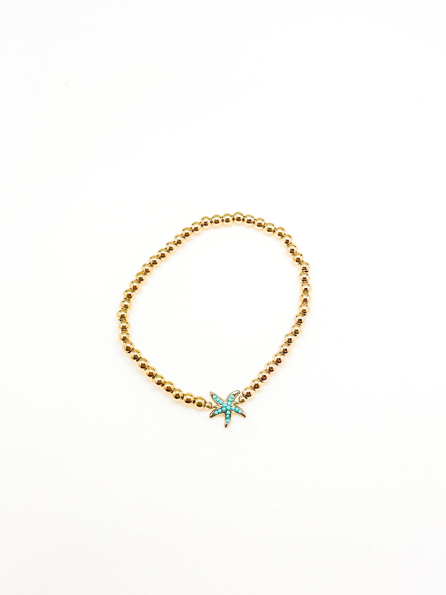 Gold beaded bracelet with a star-shaped turquoise charm on a white background