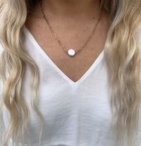 coin shaped pearl on a gold chain necklace on model.