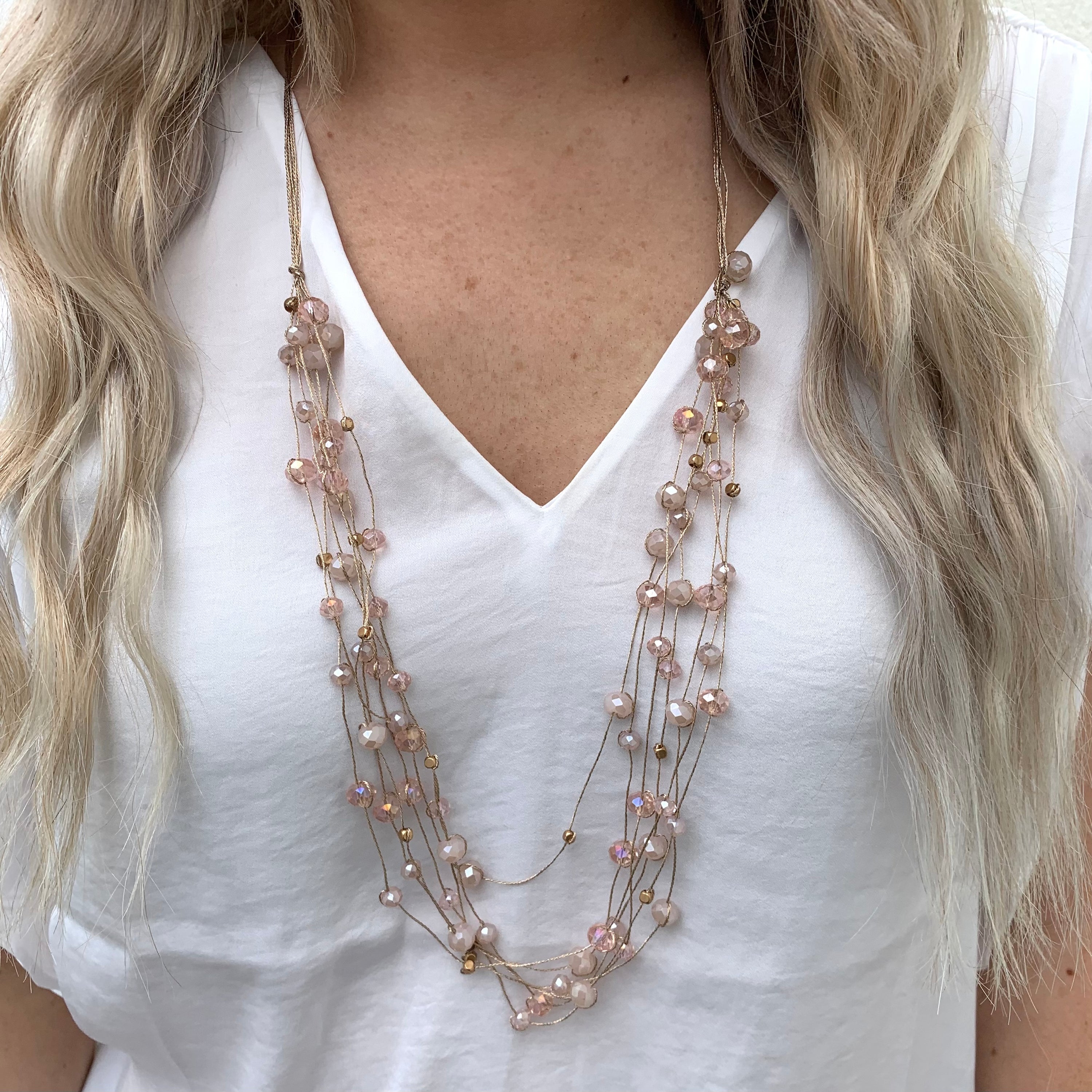 Stella beaded necklace in blush. Multiple strands of scattered beads on model. 