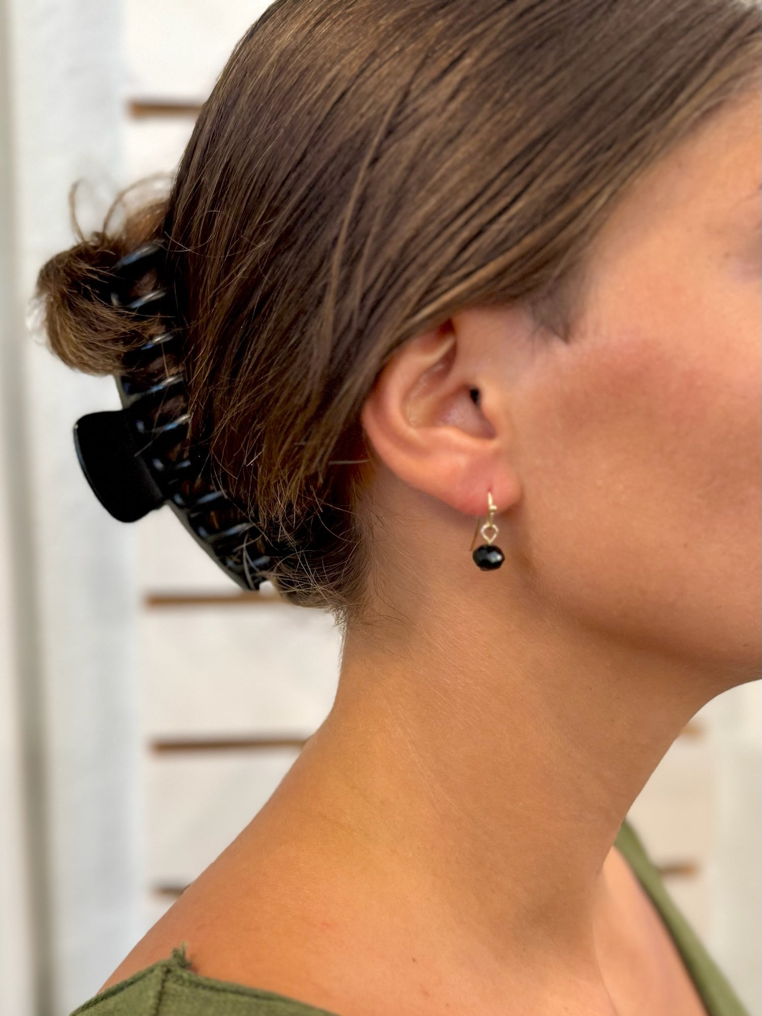 Close-up of a person's ear with a black hair clip and earrings.