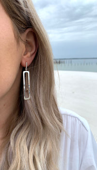 Shelby Silver earrings in ear showing silver hanging rectangular accent with a dangling gold accent chain in center