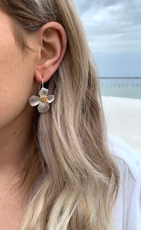 Silver magnolia flower earrings with a gold detail in the center on model