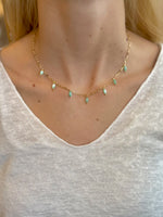 Model wearing The Lila Necklace – gold chain with seafoam green beads styled with a white knit top
