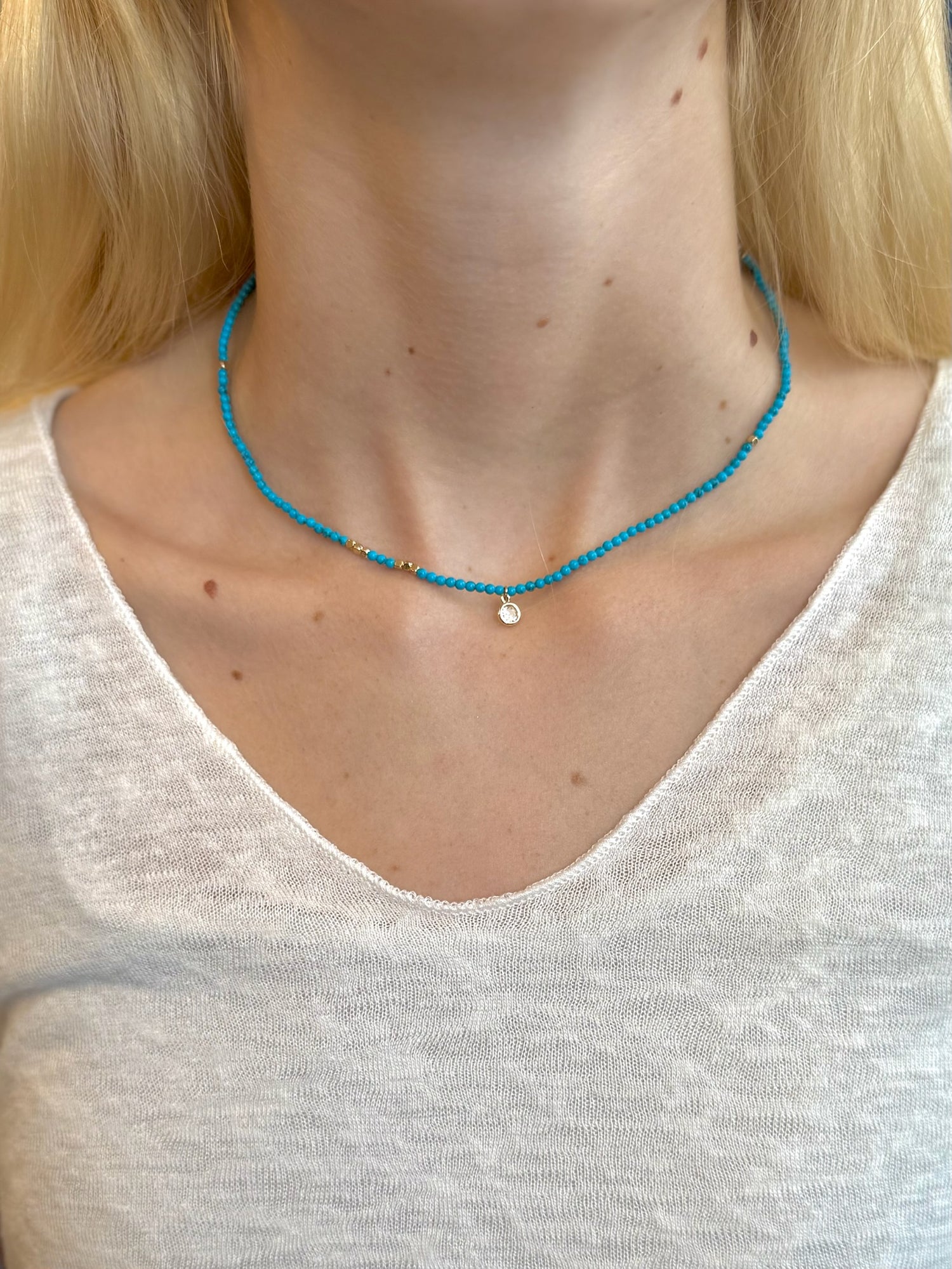 Tessa Necklace with turquoise seed beads, gold accents, and delicate charm on models neck at Ardor Boutique.