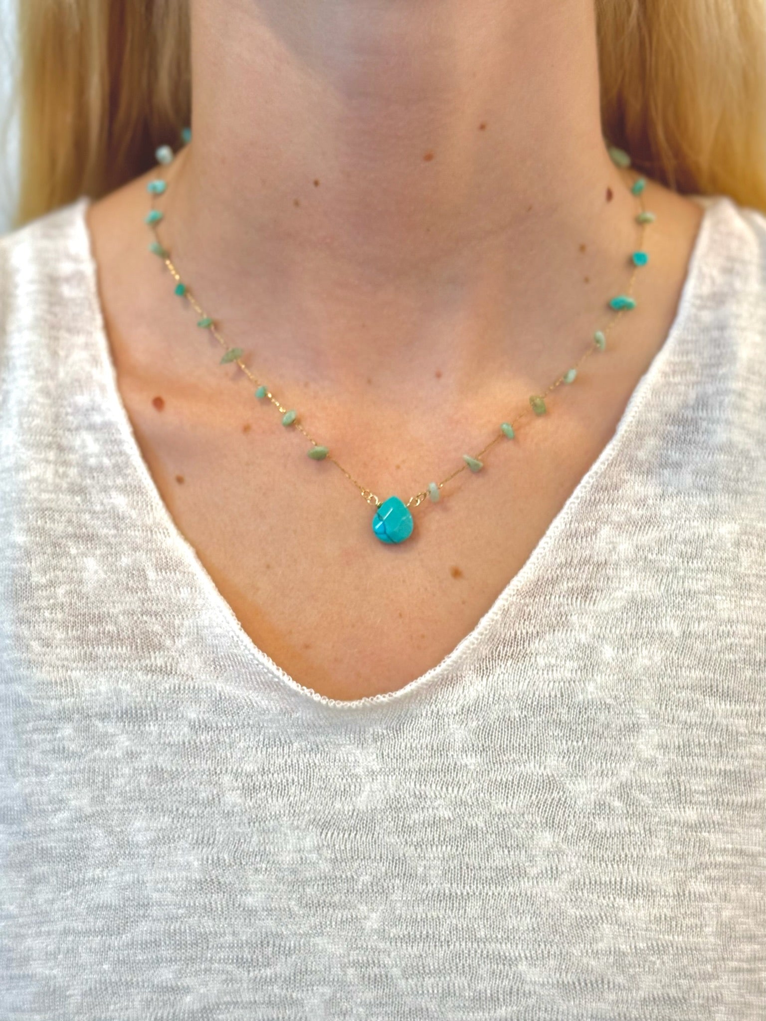 gold-toned necklace with scattered green and turquoise gemstone chips and a large central turquoise teardrop pendant