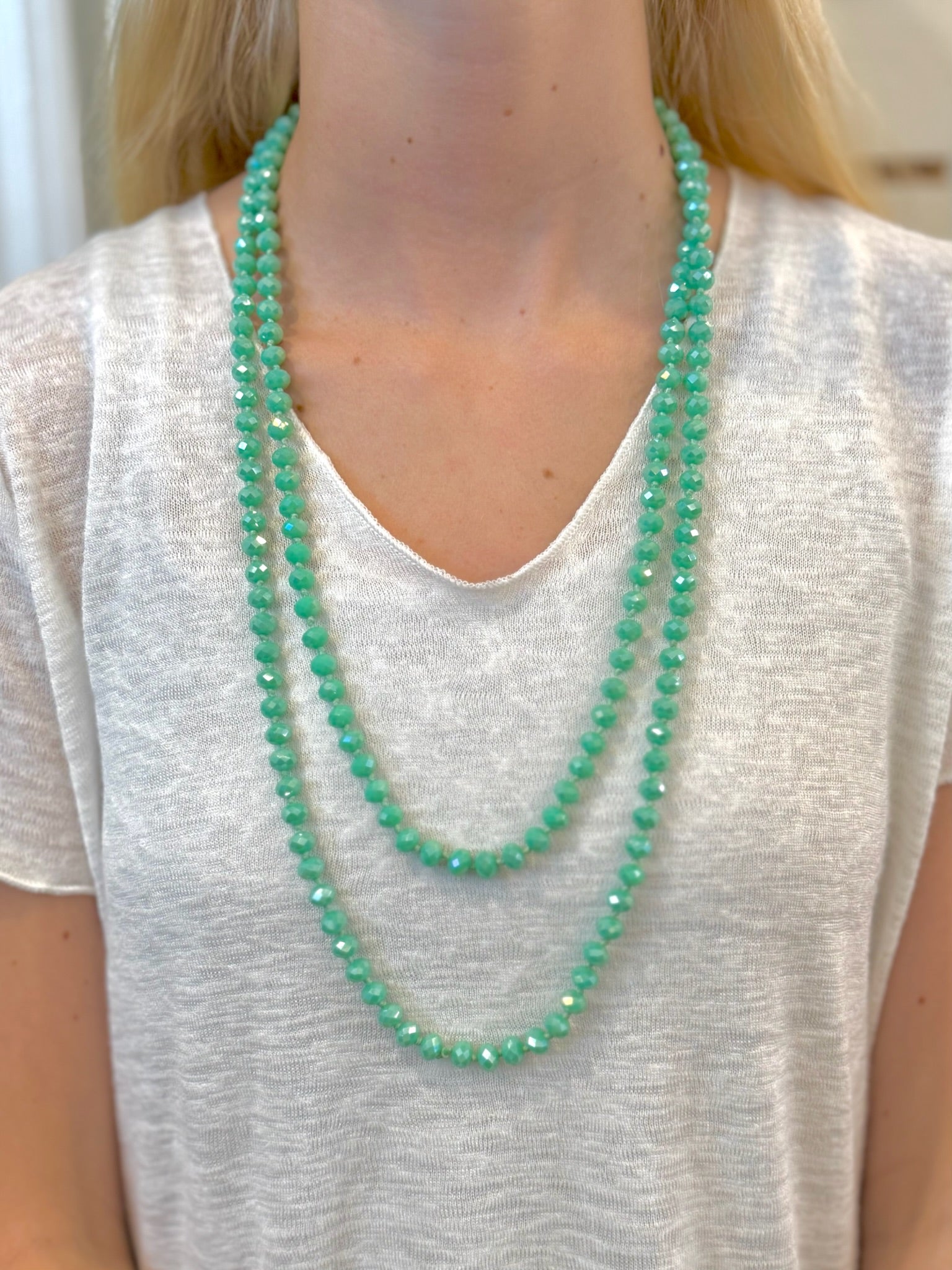 Evie Necklace with faceted aqua-green layered beads on models neck at Ardor Boutique.