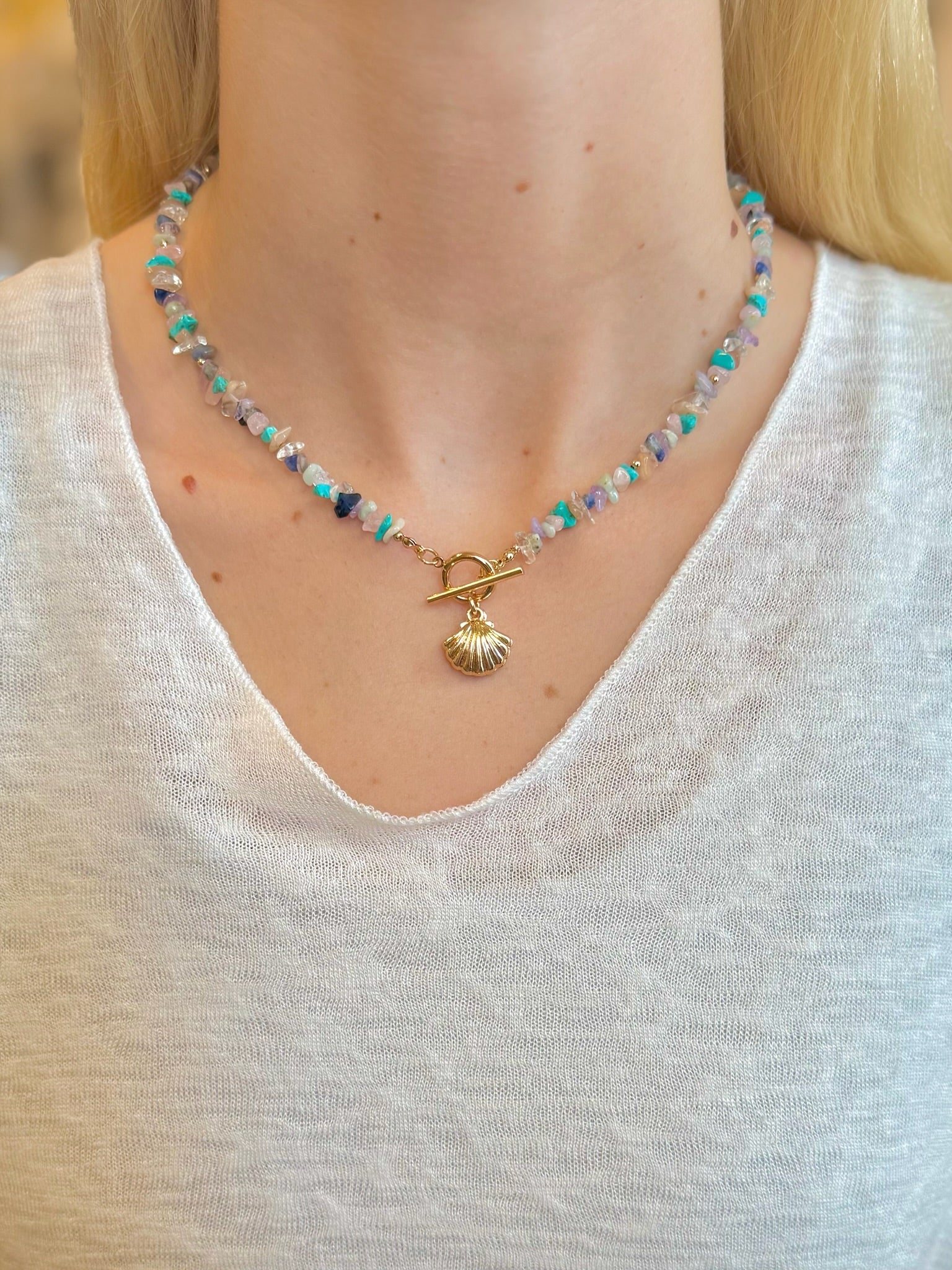 Isabelle Shell Necklace with gemstone-style beads and gold-tone shell charm on models neck 