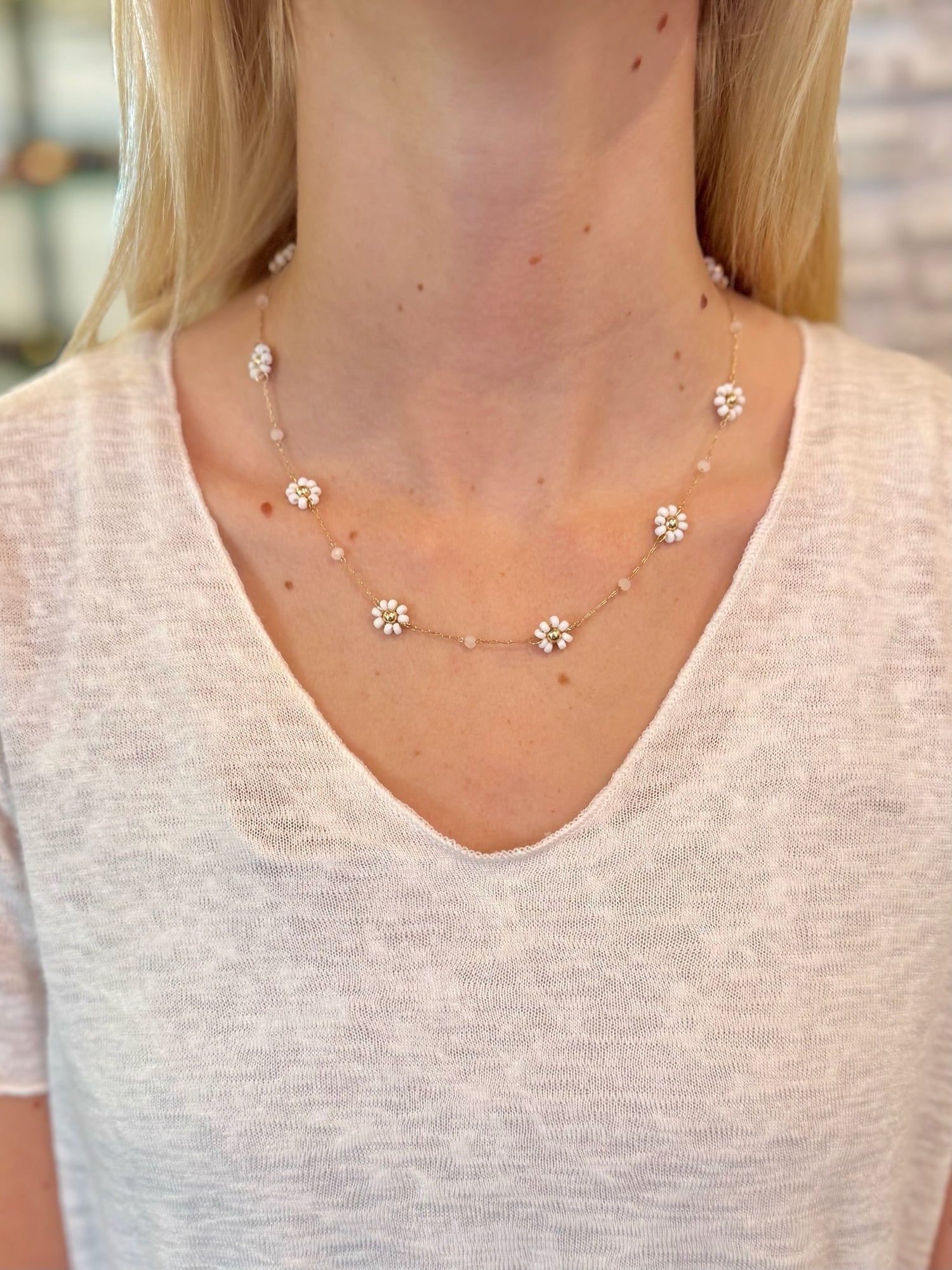 Necklace with small floral pendants worn by a person in a light-colored top.