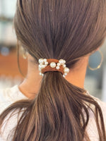 Hair tie with pearls in a ponytail against a blurred background