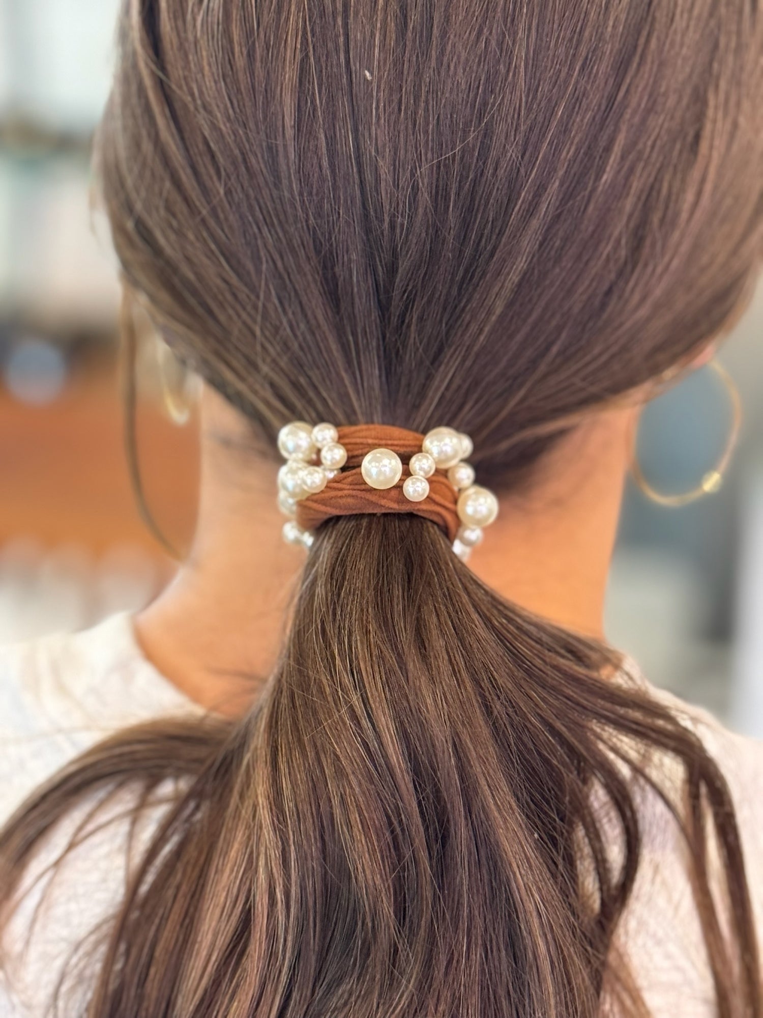Hair tie with pearls in a ponytail against a blurred background