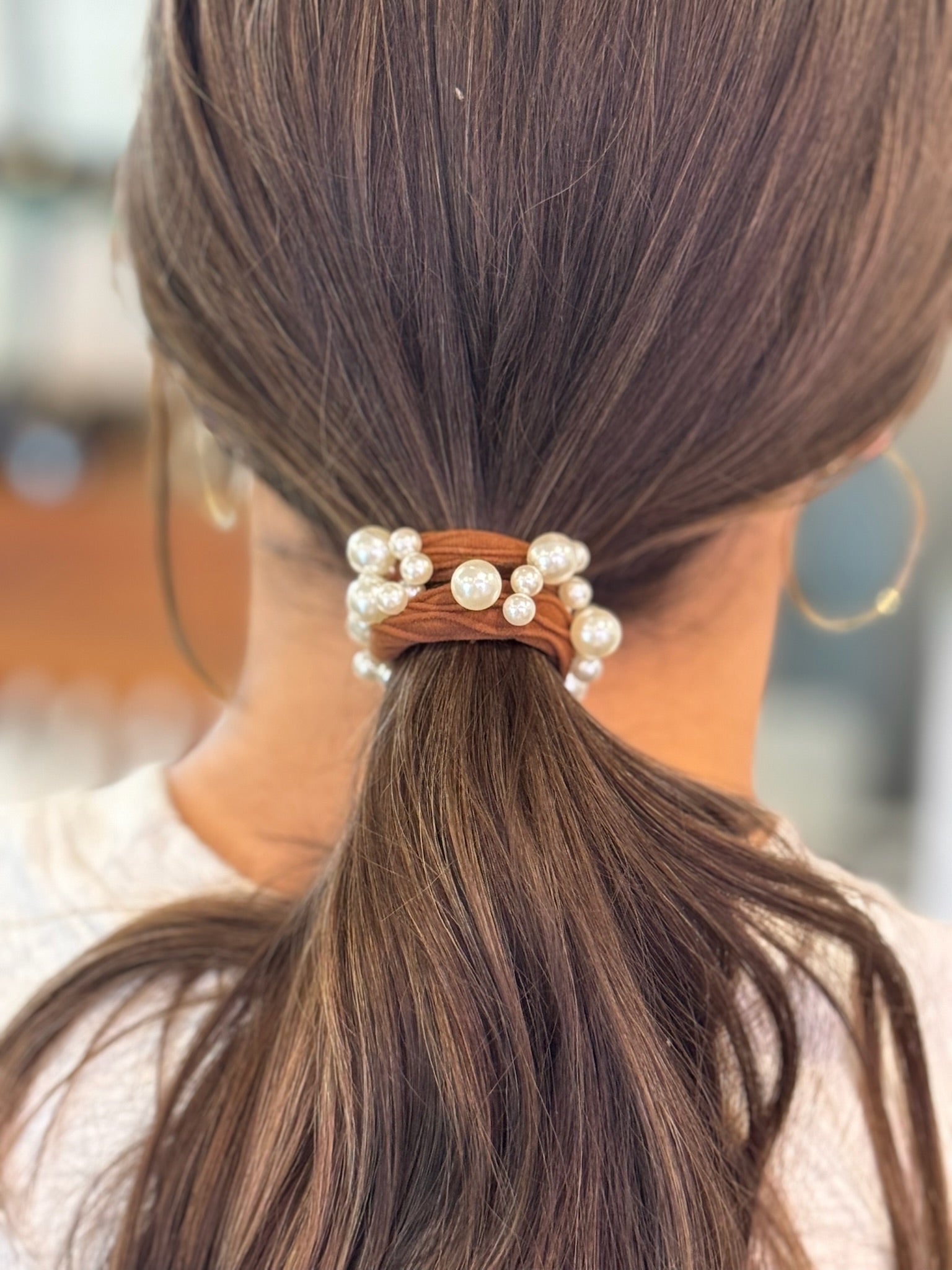 Hair tie with pearls in a ponytail against a blurred background