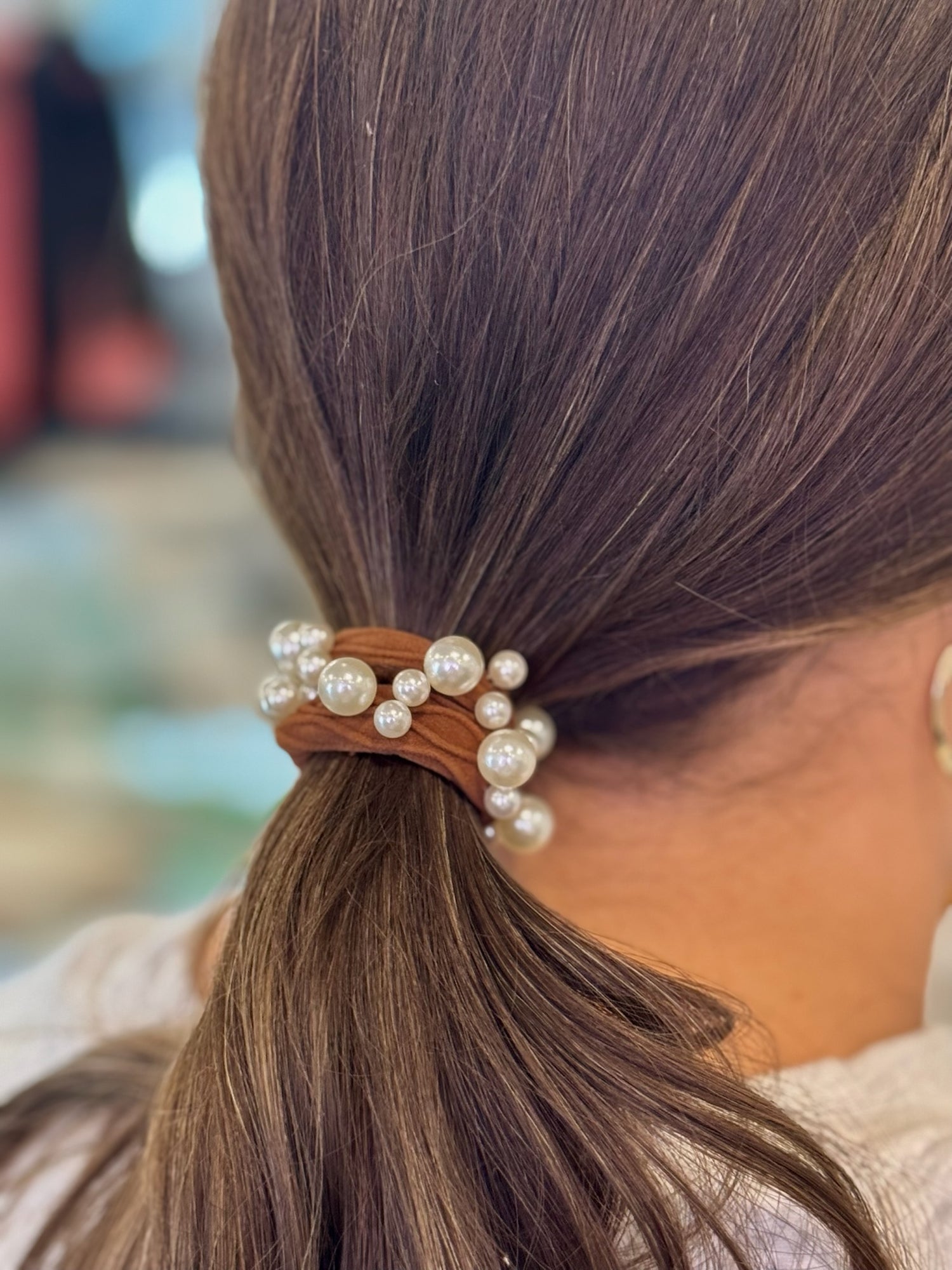 Hair tie with pearls in a ponytail against a blurred background